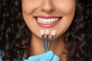 Close up of dentist comparing replacement veneers to woman’s smile