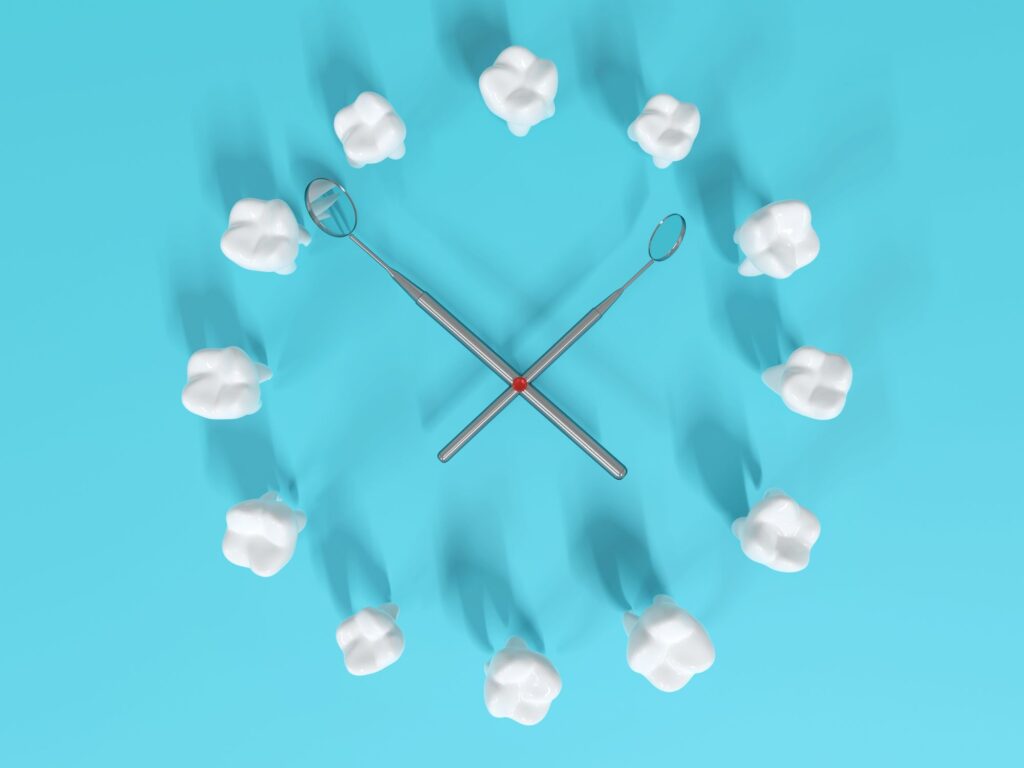 12 toy teeth arranged in a clock with dental mirrors for hands